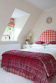 Kopfteil mit Gingham-Karomuster auf einem Doppelbett im Dachgeschoss eines Cottage in Kent, England, UK