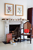 Gift wrapped presents with wicker chair and silverware below artwork at fireplace in London home, UK