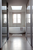 White freestanding bath in tiled bathroom of contemporary London home, UK