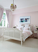 Chinaware artwork above white painted double bed in pastel pink bedroom of contemporary London home, UK