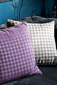 Contrasting dog-tooth checked cushions on black sofa in London home, UK