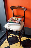 Spectacles and books on upholstered chair in hallway of London home England UK
