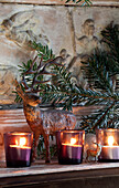 Reindeer statue and lit tealights on mantlepiece in London home, England, UK