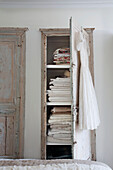 Folded sheets and bed covers in salvaged cupboard, London townhouse, England, UK