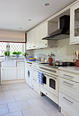 White fitted kitchen with leaded window in Sussex farmhouse, England, UK