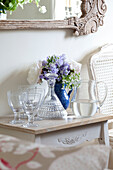 Jug of water and glasses on side table with cut flowers in Sussex cottage, England, UK