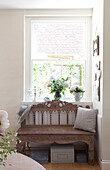 Carved wooden bench at window of Sussex cottage, England, UK