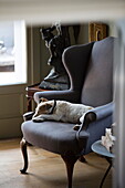 Hund schläft auf einem gepolsterten Ohrensessel in einem historischen Landhaus in Sussex England UK