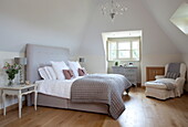 Hellgraue Bettdecke und Kopfteil auf einem Bett in einem Zimmer mit Holzboden, Haus in Kent, England, Vereinigtes Königreich