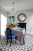 Blue and Ghost dining chairs at table on patterned rug in London townhouse England UK