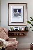 Kunstwerk über einem wandmontierten Regal mit Sessel im Wohnzimmer eines Familienhauses in Kent, England, UK