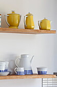 Teekannen und Zuckerdosen auf offenen Holzregalen in der Küche eines Einfamilienhauses in Kent England UK
