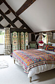 Tapestry quilt on double bed in attic bedroom of timber-framed Herefordshire home, England, UK