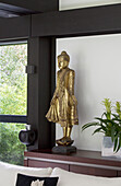 Goldene Buddha-Statue auf einem Sideboard in einem modernen Haus im Südwesten Londons, England, Vereinigtes Königreich