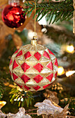 Gold and red bauble hangs on Christmas tree in Chilterns home, England, UK