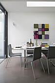 Graue Esszimmerstühle am Tisch mit modernen Kunstwerken in einem modernen Haus in Brighton, East Sussex, England, UK