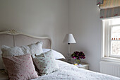 Gingham and floral cushions on double bed in Burwash home, East Sussex, England, UK