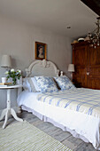 Toile-de-Jouy-Kissen und karierter Bezug auf einem Bett mit geschnittenen Rosen neben einem Haus in West Sussex, England, Vereinigtes Königreich