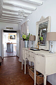 Pair of matching lamps on painted sideboard in hallway of West Sussex home, England, UK