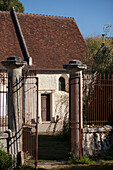 View through wrought iron gates to sunlit exterior of French cottage in the Loire, France