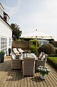 Gartenmöbel aus Weidengeflecht mit Sonnenschirm auf der Terrasse eines Hauses in West Maling, Kent, England, UK