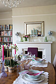 Wooden dining table with fireplace and bookshelf in London home England UK