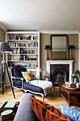 Reclining armchair with bookcase at fireside in contemporary London home, England, UK