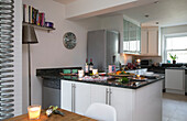 Upright fridge and lit candles in open plan kitchen of London home, England, UK