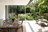 Dining table with patio furniture in garden extension of Oxfordshire home England UK
