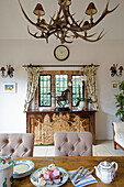 Teapot and plates on dining table with equestrian statue on sideboard in London home, UK