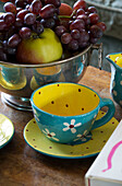 Geblümte Teetasse mit einer Schale Weintrauben auf einem Holztisch in Camber cottage East Sussex England UK
