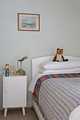 Kuscheltier auf Einzelbett mit gepunkteter Decke und Beistellschrank in Presteigne cottage Wales UK
