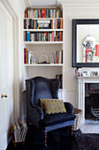 Schwarzer Samtsessel mit eingelassenen Bücherregalen im Wohnzimmer eines Londoner Stadthauses, England, UK