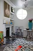 Fireplace with black fender and porthole window in living room of London home, England, UK