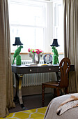 Ein Paar grüne Papageienlampen auf einem Schreibtisch mit Stuhl am Fenster in einem Londoner Haus, England, UK