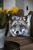 Wolfskissen auf braunem Sofa mit Schnittblumen in modernem Wohnzimmer in Sussex, England, UK