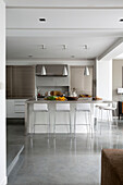 Bar stools at kitchen island with metallic pendant lights in contemporary Sussex home, England, UK