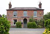 Detached brick house with hedge and driveway   UK