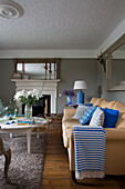 Blau gestreifte Decke auf gelbem Sofa im Wohnzimmer mit Couchtisch in einem britischen Haus