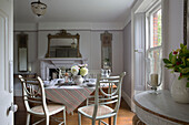 Gestreifte Tischdecke auf Esstisch mit bemalten Korbstühlen in einem britischen Haus