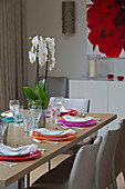 Esszimmerstühle am Tisch mit hellen Tellern und Orchidee in einem Haus in Großbritannien