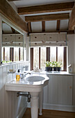 Waschbecken und Spülbecken im weiß getäfelten Badezimmer eines Bauernhauses in Suffolk, England, UK