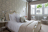 Silk cushions on double bed in room with patterned wallpaper in Hertfordshire home,  England,  UK