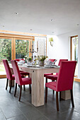 Rosafarbene Esszimmerstühle an einem hellen Holztisch im Landhaus in Sussex, England UK