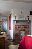 Exposed brick fireplace with pair of candlesticks in London bedroom detail,  England,  UK