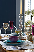 Buntes Glas, Schale und Teller mit silbernem Kerzenständer auf Esstisch in Londoner Wohnung, England, UK