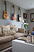 Wandmontierte Gitarren über dem Sofa im Londoner Wohnzimmer, England, UK