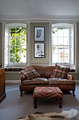 Tartan cushions on brown leather two-seater sofa in Surrey home,  England,  UK