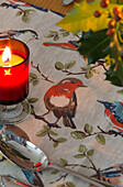 Angezündete Kerze auf Tischläufer mit Rotkehlchen in Dronfield home Derbyshire England UK