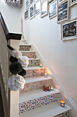 Framed photographs above papered staircase with lit candles in Laughton home  Sheffield  UK